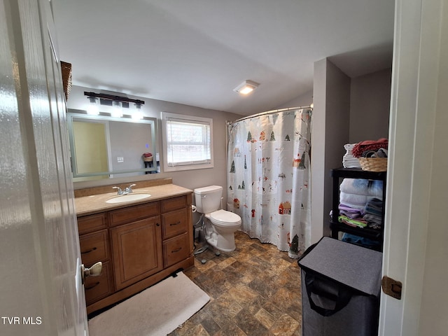 full bathroom with stone finish flooring, a shower with shower curtain, vanity, and toilet