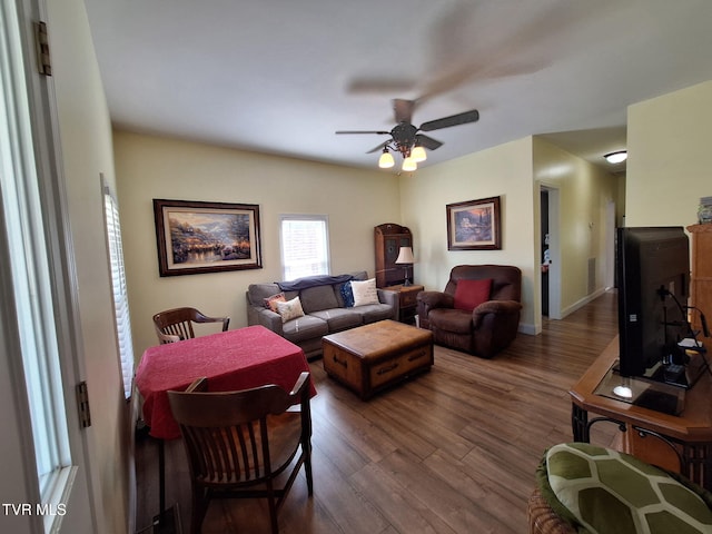 living area with a ceiling fan, dark wood-style flooring, and baseboards