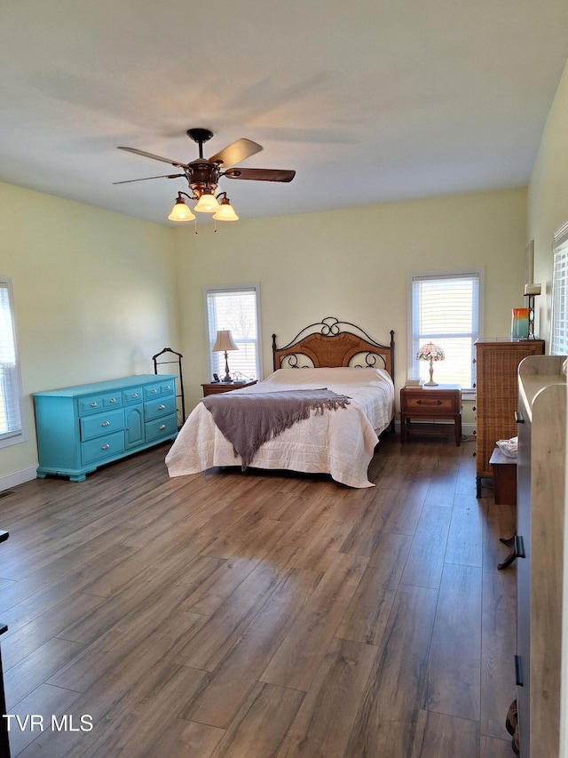 bedroom with dark wood-style floors, multiple windows, and ceiling fan