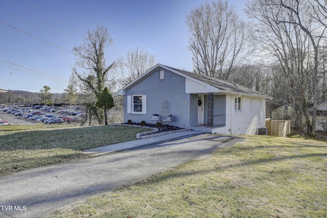 bungalow-style house with brick siding, a front lawn, and central AC unit