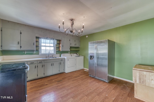 kitchen with separate washer and dryer, stainless steel refrigerator with ice dispenser, light wood-style floors, open shelves, and a sink