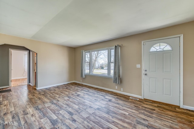 entryway with arched walkways, wood finished floors, visible vents, and baseboards