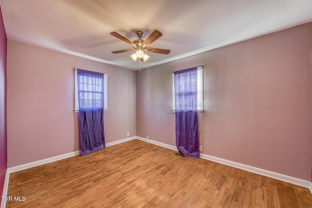 empty room featuring wood finished floors, a ceiling fan, and baseboards