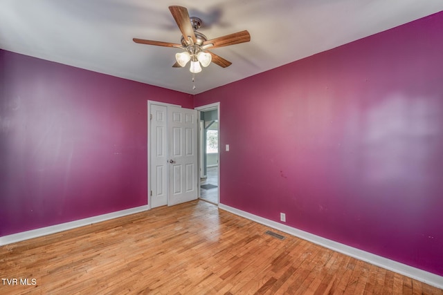 unfurnished room with a ceiling fan, baseboards, visible vents, and hardwood / wood-style floors