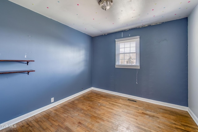 unfurnished room with hardwood / wood-style flooring, baseboards, and visible vents