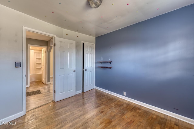 unfurnished bedroom with a closet, wood-type flooring, and baseboards