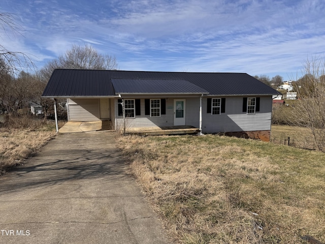 ranch-style home featuring metal roof, driveway, an attached carport, and a front lawn