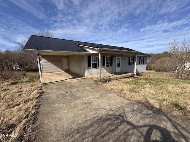 ranch-style house with an attached carport, concrete driveway, and metal roof