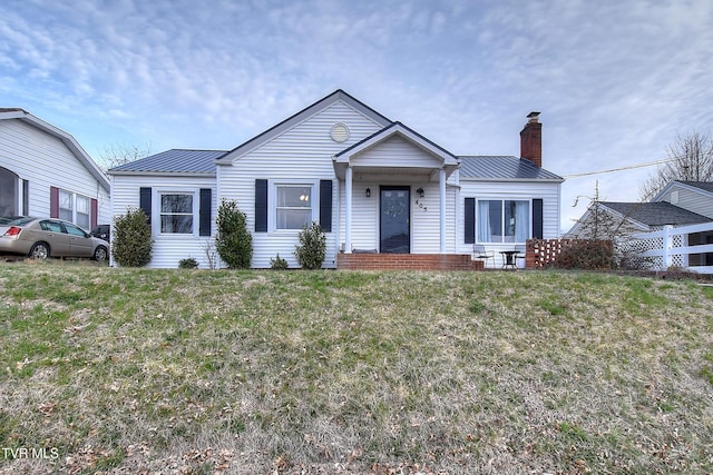 view of front of property with a standing seam roof, metal roof, a chimney, and a front lawn