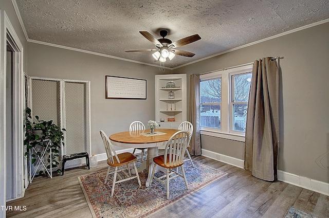 dining space with a textured ceiling, ornamental molding, and wood finished floors