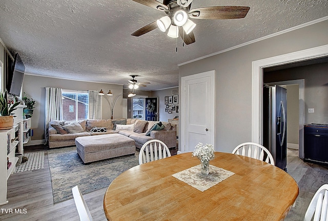 dining room with a textured ceiling, ceiling fan, ornamental molding, and wood finished floors