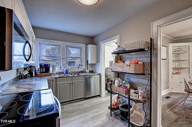 kitchen featuring range with electric stovetop, dishwasher, light wood finished floors, and a sink