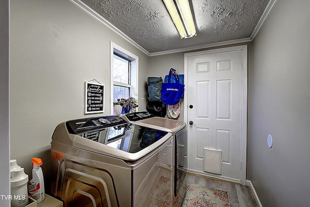 clothes washing area featuring laundry area, ornamental molding, wood finished floors, independent washer and dryer, and a textured ceiling