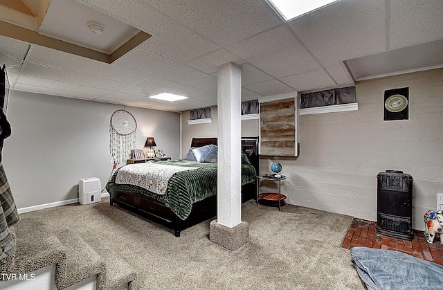 carpeted bedroom featuring a drop ceiling and baseboards