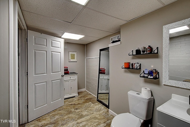 bathroom with toilet, vanity, a paneled ceiling, and baseboards