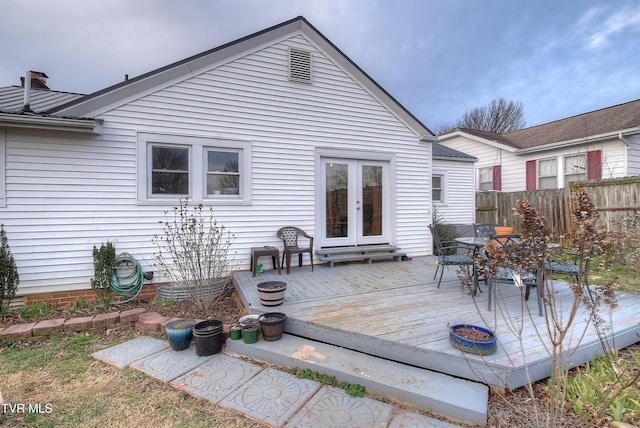 rear view of property featuring french doors, fence, a deck, and metal roof