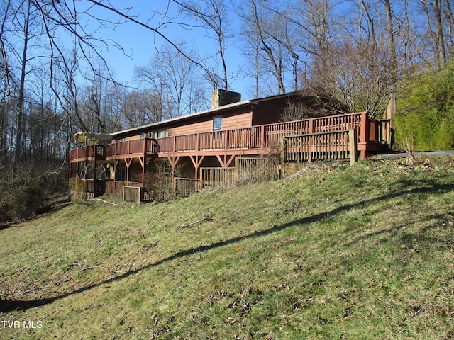 back of property with a yard, a chimney, and a wooden deck