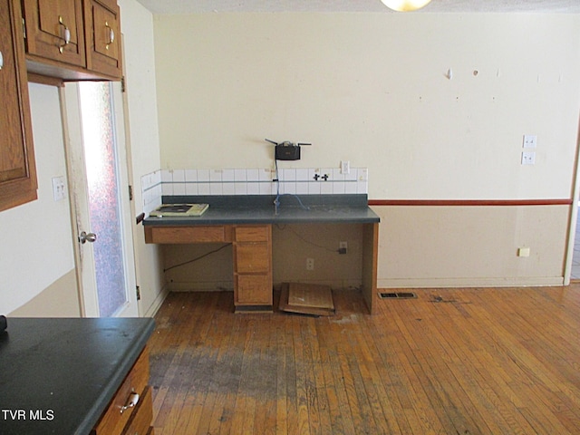 unfurnished office with baseboards, visible vents, and dark wood-type flooring