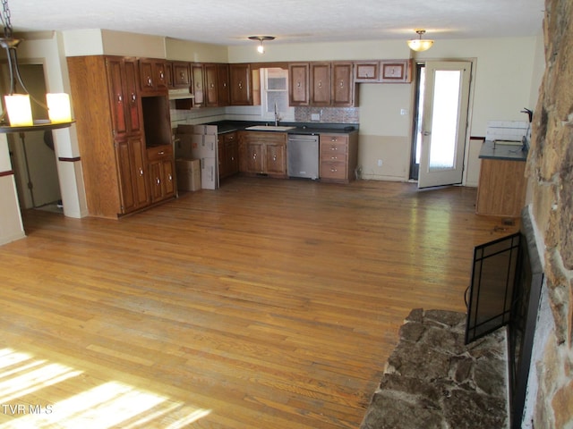 kitchen featuring pendant lighting, brown cabinets, dark countertops, wood finished floors, and dishwasher