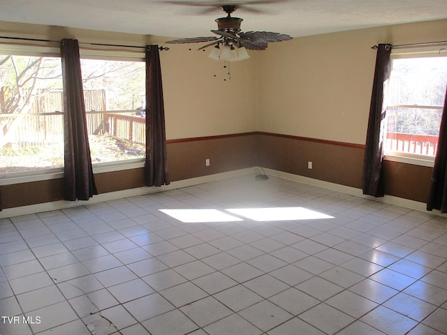 unfurnished room with ceiling fan, baseboards, and light tile patterned flooring