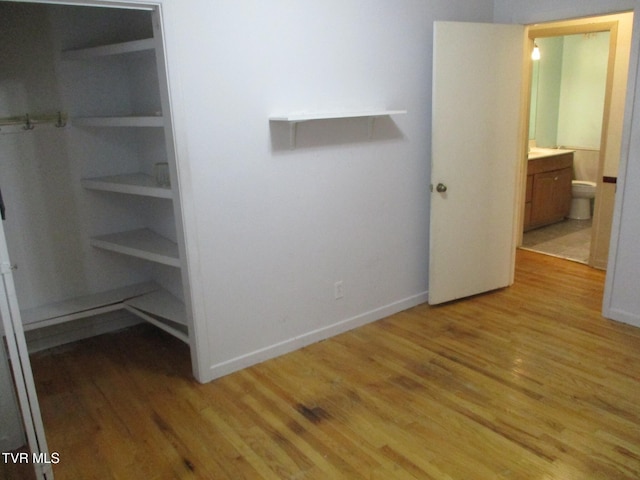 interior space with light wood finished floors, connected bathroom, and baseboards