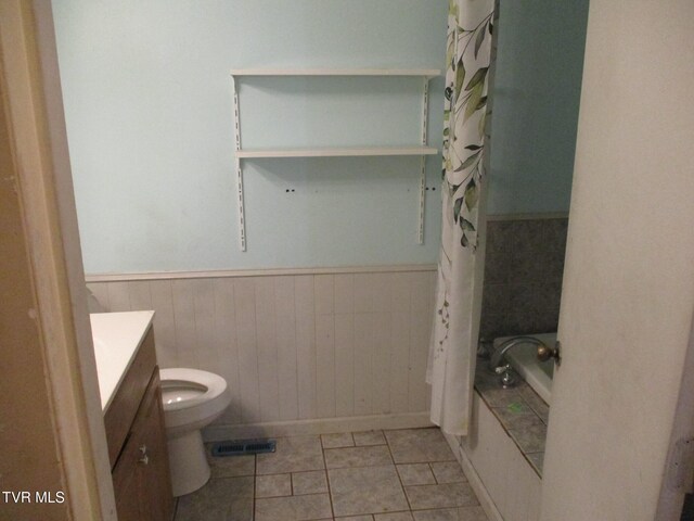 bathroom with toilet, vanity, visible vents, wainscoting, and shower / bath combo with shower curtain