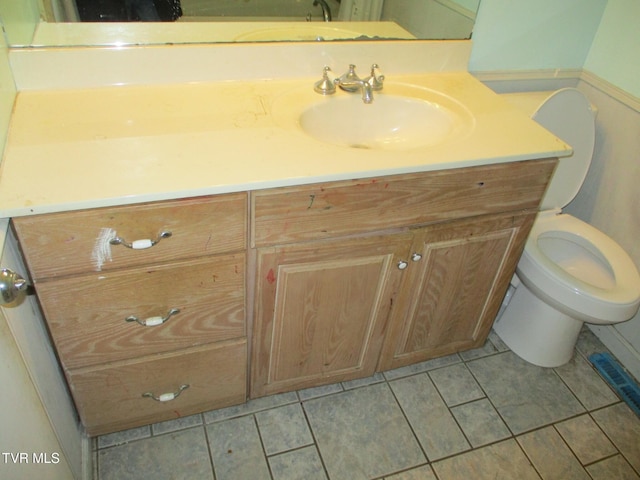 half bath with toilet, tile patterned flooring, and vanity