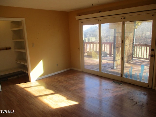 unfurnished room with wood finished floors, visible vents, and baseboards