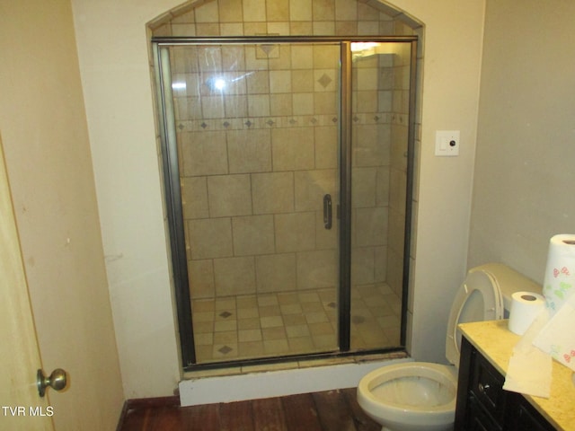 bathroom with toilet, a stall shower, wood finished floors, and vanity