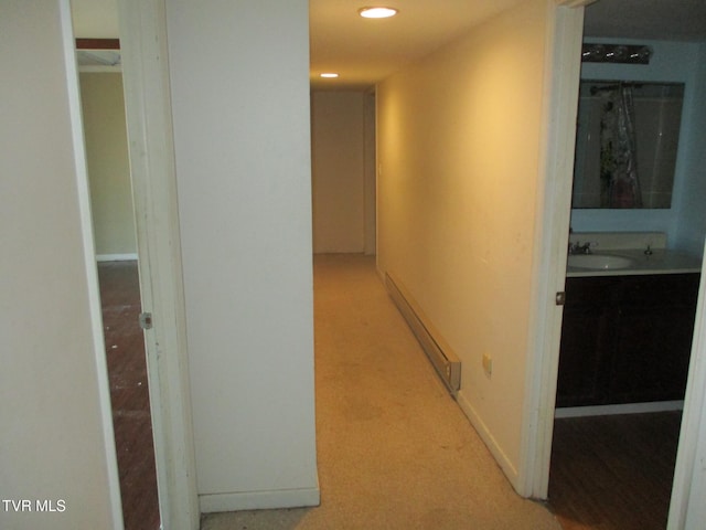 corridor featuring baseboards, light carpet, a sink, and recessed lighting