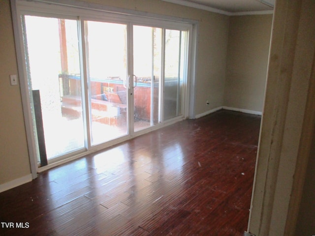 spare room with dark wood-style flooring and baseboards