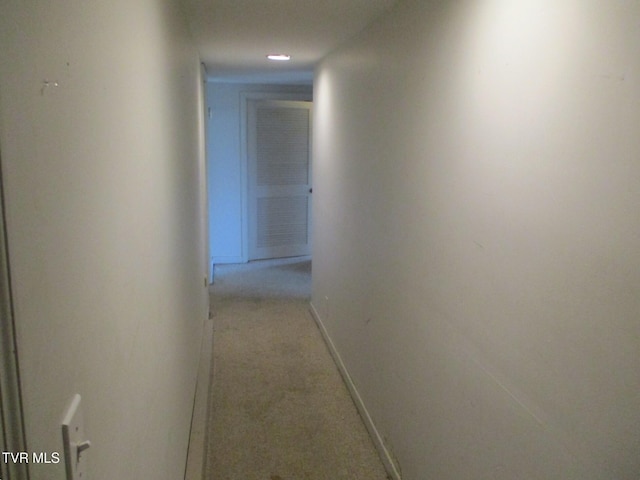 hall featuring baseboards and light colored carpet