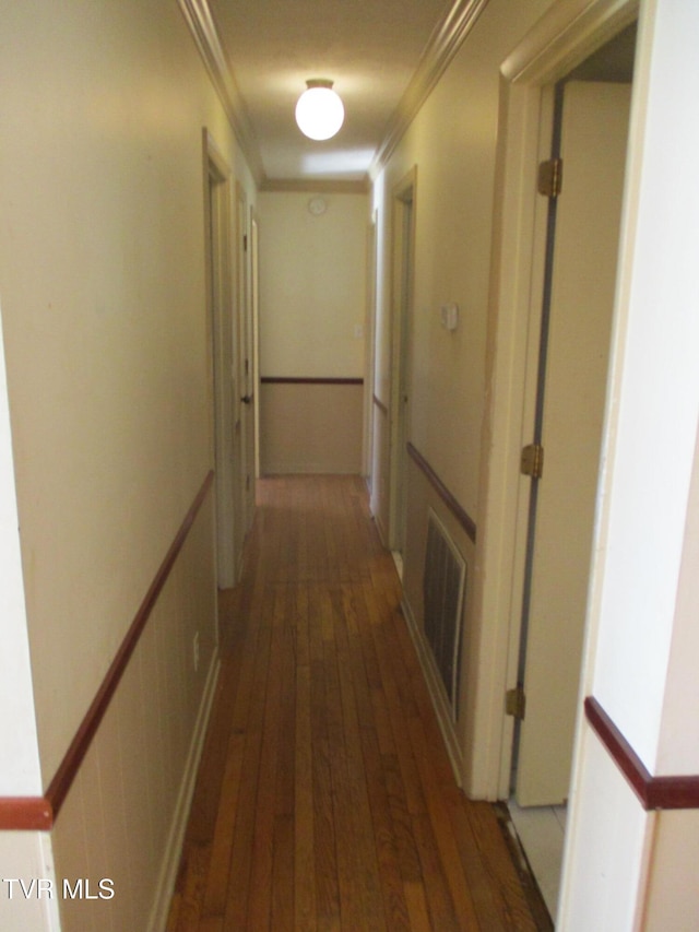 hall featuring dark wood finished floors, a wainscoted wall, visible vents, and crown molding