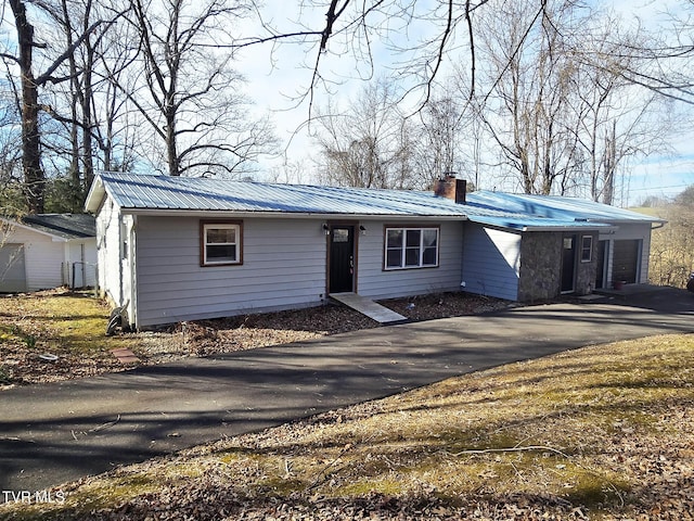 view of front of property with metal roof, aphalt driveway, and a chimney