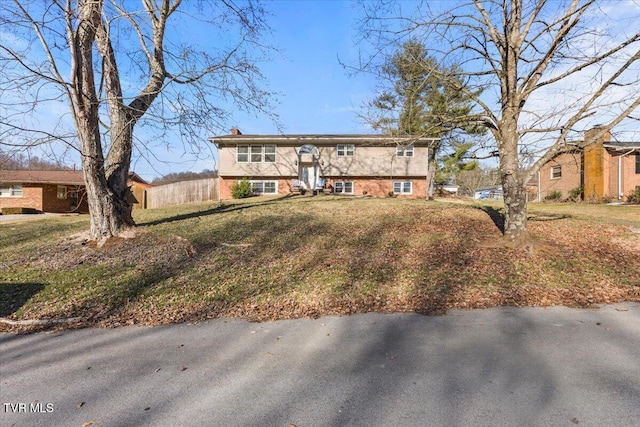 raised ranch featuring a front lawn and brick siding