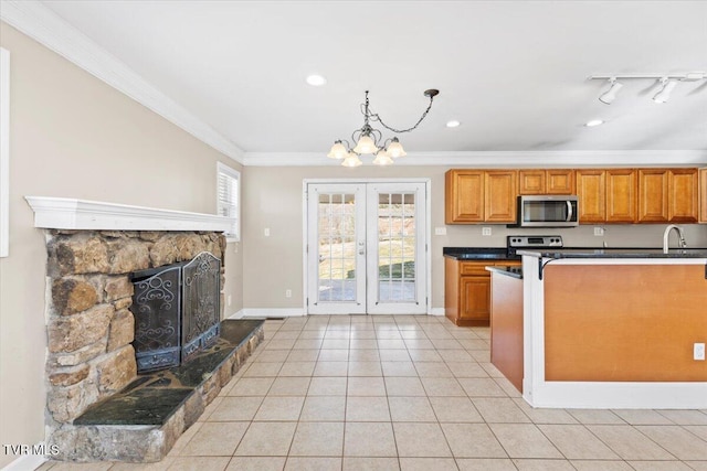 kitchen with light tile patterned floors, brown cabinetry, dark countertops, appliances with stainless steel finishes, and ornamental molding