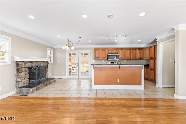 kitchen with ornamental molding, open floor plan, stainless steel microwave, and a healthy amount of sunlight