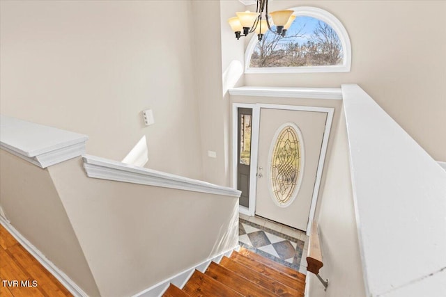 foyer entrance featuring stairs, a wealth of natural light, and an inviting chandelier