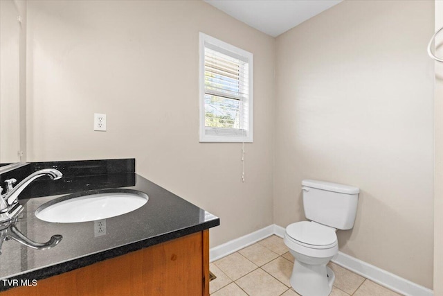 half bathroom with baseboards, vanity, toilet, and tile patterned floors