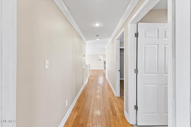 hallway featuring light wood-style floors, baseboards, crown molding, and recessed lighting