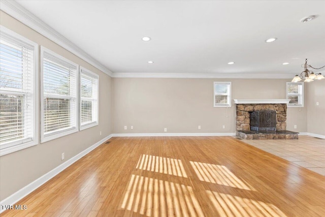 unfurnished living room with light wood-style floors, a wealth of natural light, a fireplace, and crown molding