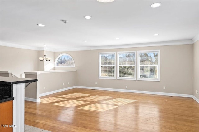 unfurnished living room with a notable chandelier, crown molding, recessed lighting, light wood-type flooring, and baseboards