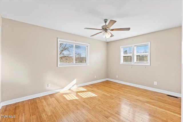 unfurnished room featuring baseboards, a wealth of natural light, and light wood-style floors