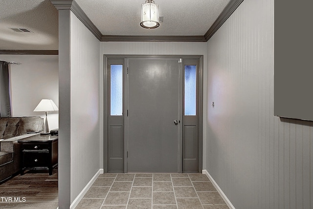 entrance foyer with visible vents, a textured ceiling, baseboards, and ornamental molding