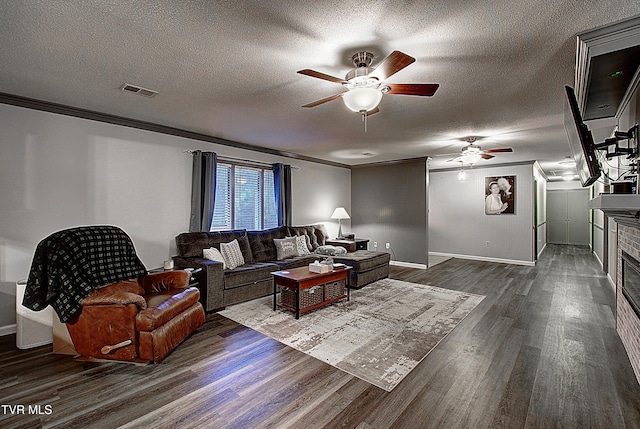 living area with a ceiling fan, visible vents, dark wood-style flooring, ornamental molding, and a textured ceiling