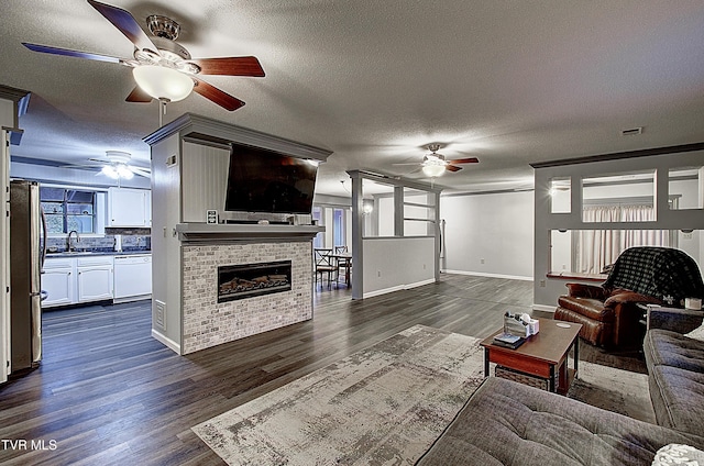 living room featuring ceiling fan, visible vents, dark wood-style flooring, and a textured ceiling