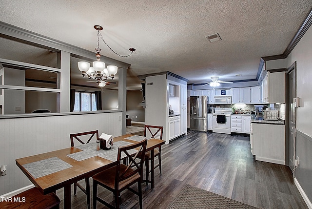 dining space with dark wood-style floors, visible vents, ornamental molding, a textured ceiling, and ceiling fan with notable chandelier