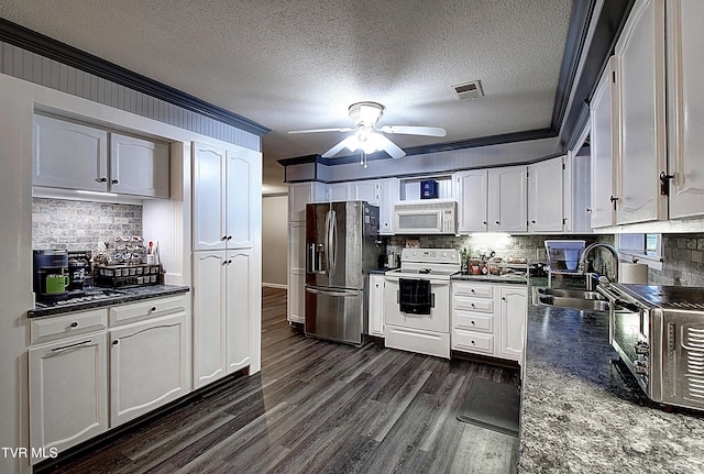 kitchen featuring dark countertops, visible vents, dark wood-type flooring, white appliances, and a sink