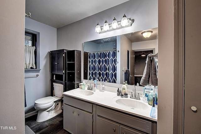 full bathroom with double vanity, wood finished floors, toilet, and a sink