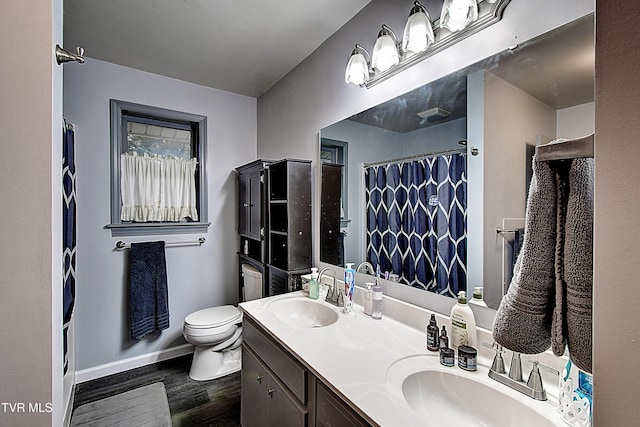 full bathroom featuring double vanity, wood finished floors, toilet, and a sink